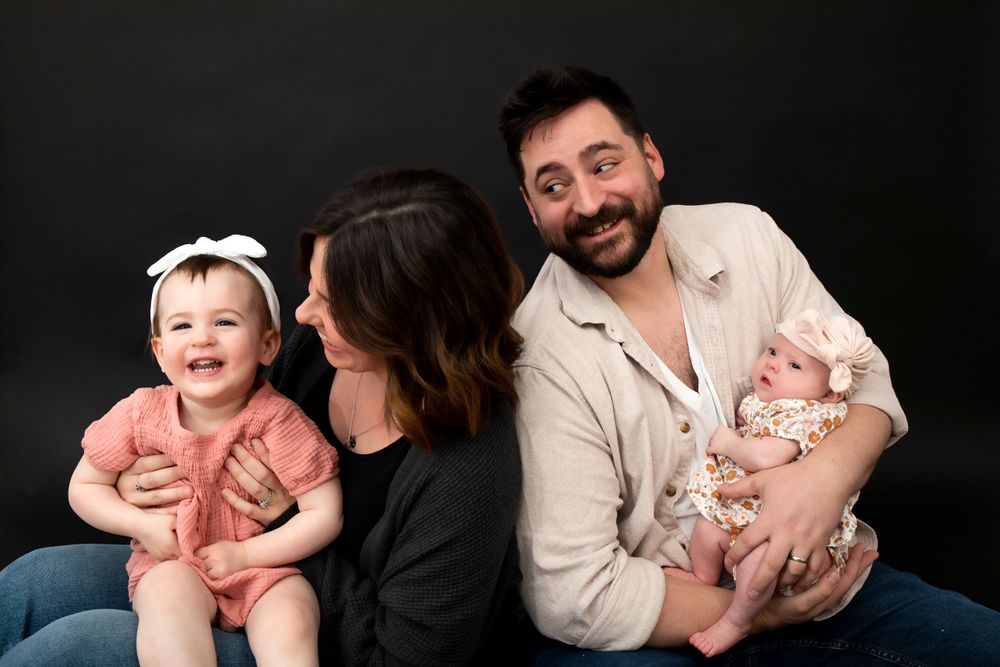 Studio portrait of a happy family with two young children against dark background.