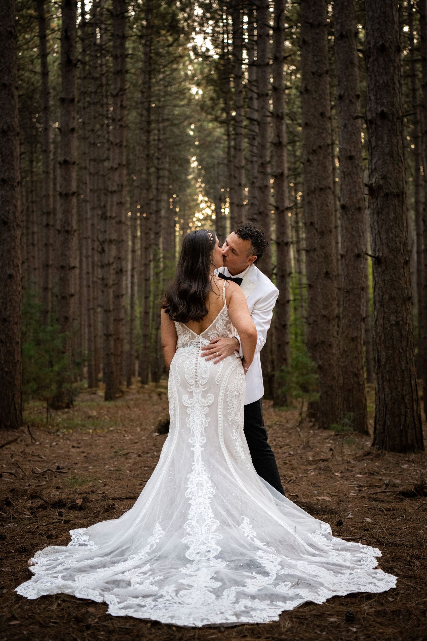 An intimate wedding portrait in a pine forest with a stunning lace train dress.