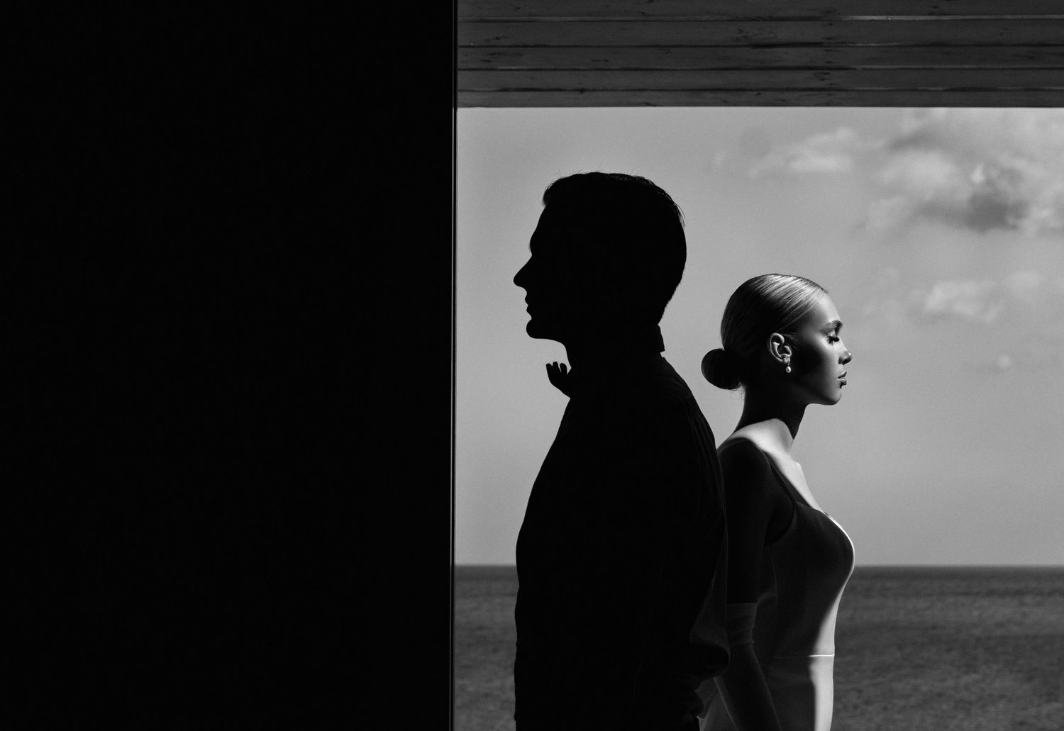 Artistic black and white silhouette portraits against ocean backdrop.