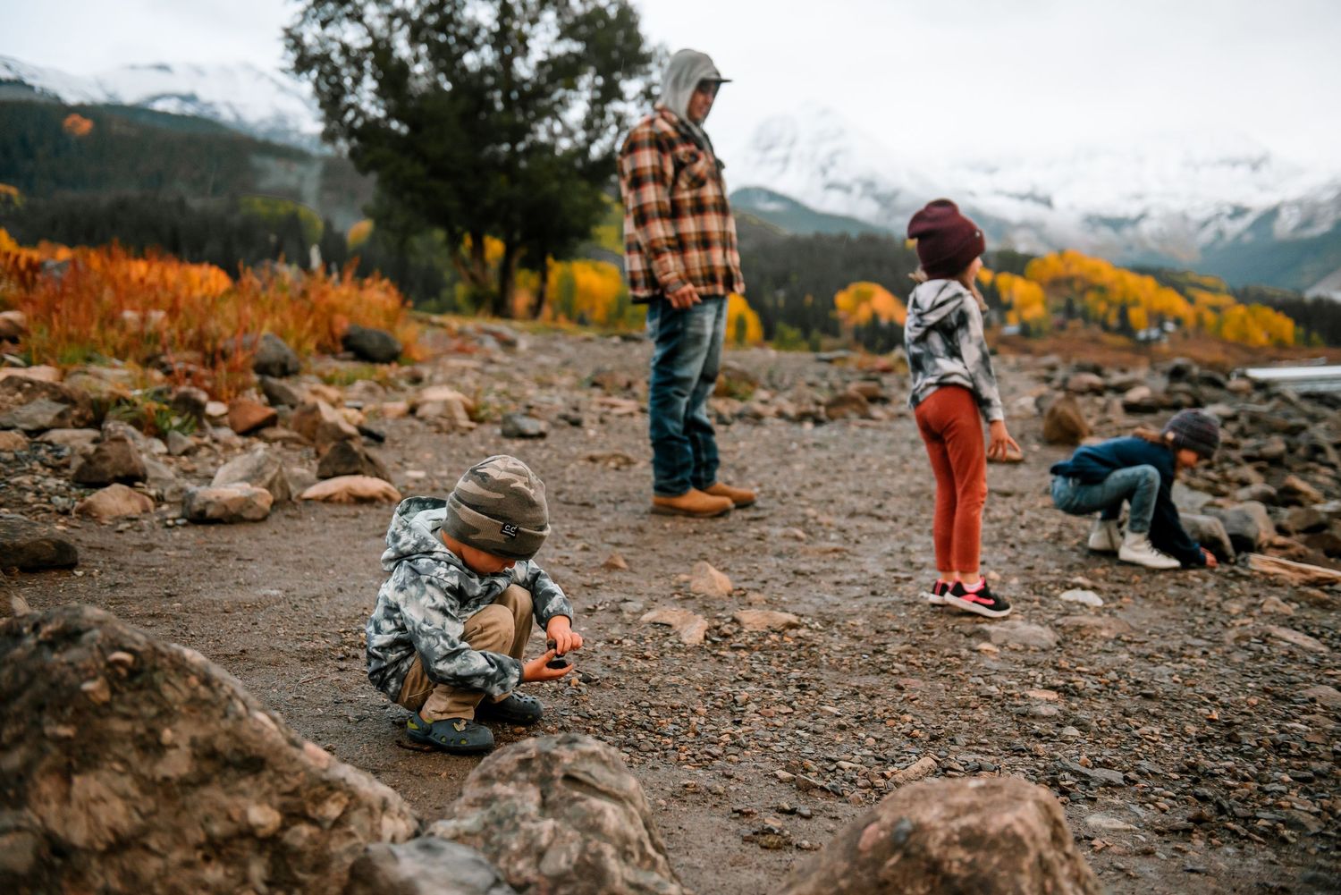Outdoor adventure scene by a mountain lake with rocky shore and snow-covered peaks.
