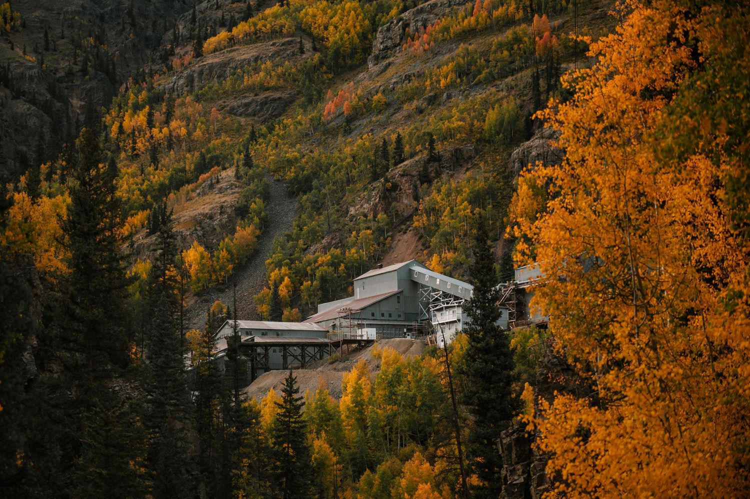 Mountain lodge nestled among vibrant fall colors in a scenic valley landscape.