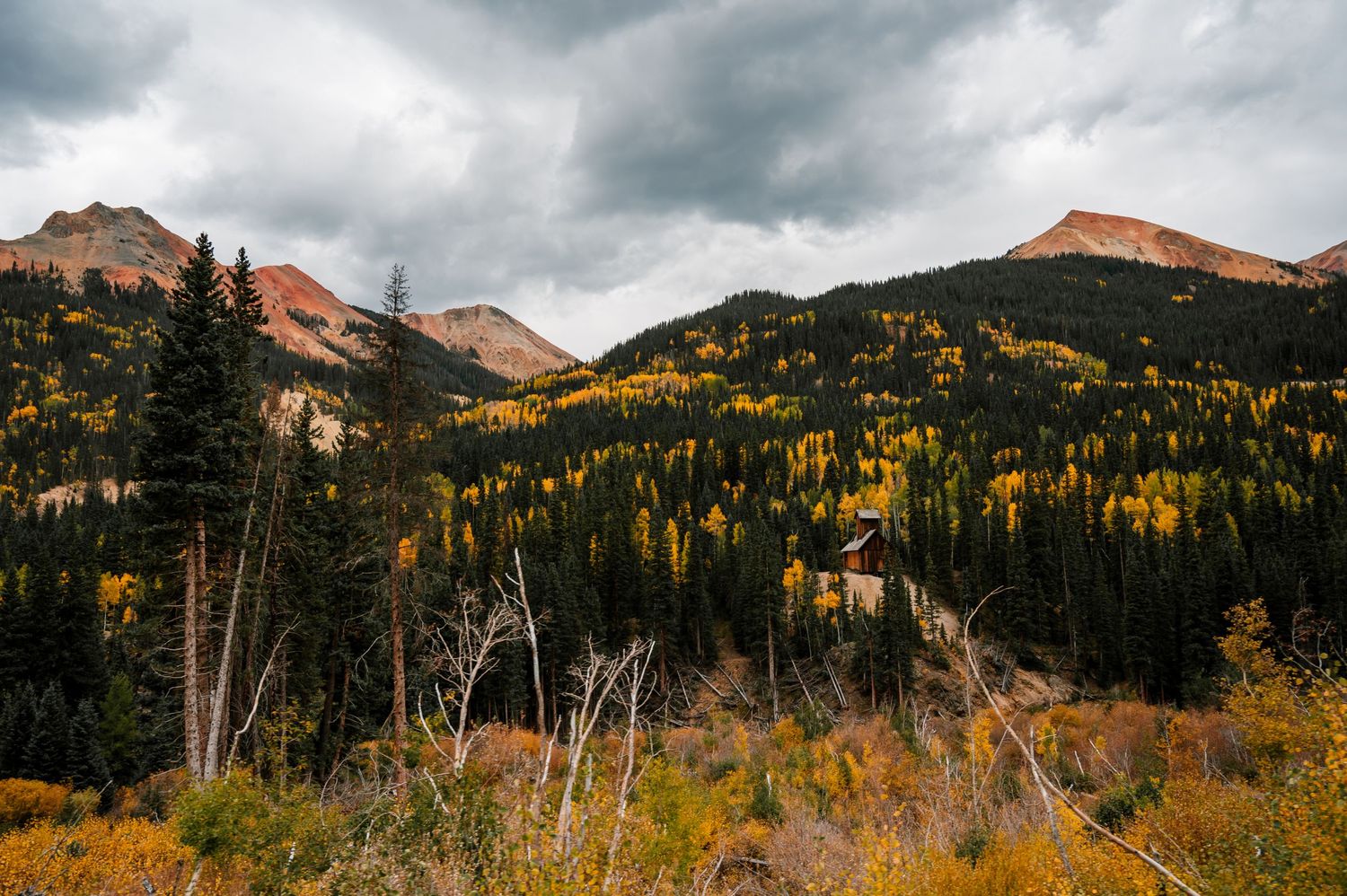 Dramatic mountain landscape with autumn colors under moody cloudy skies.