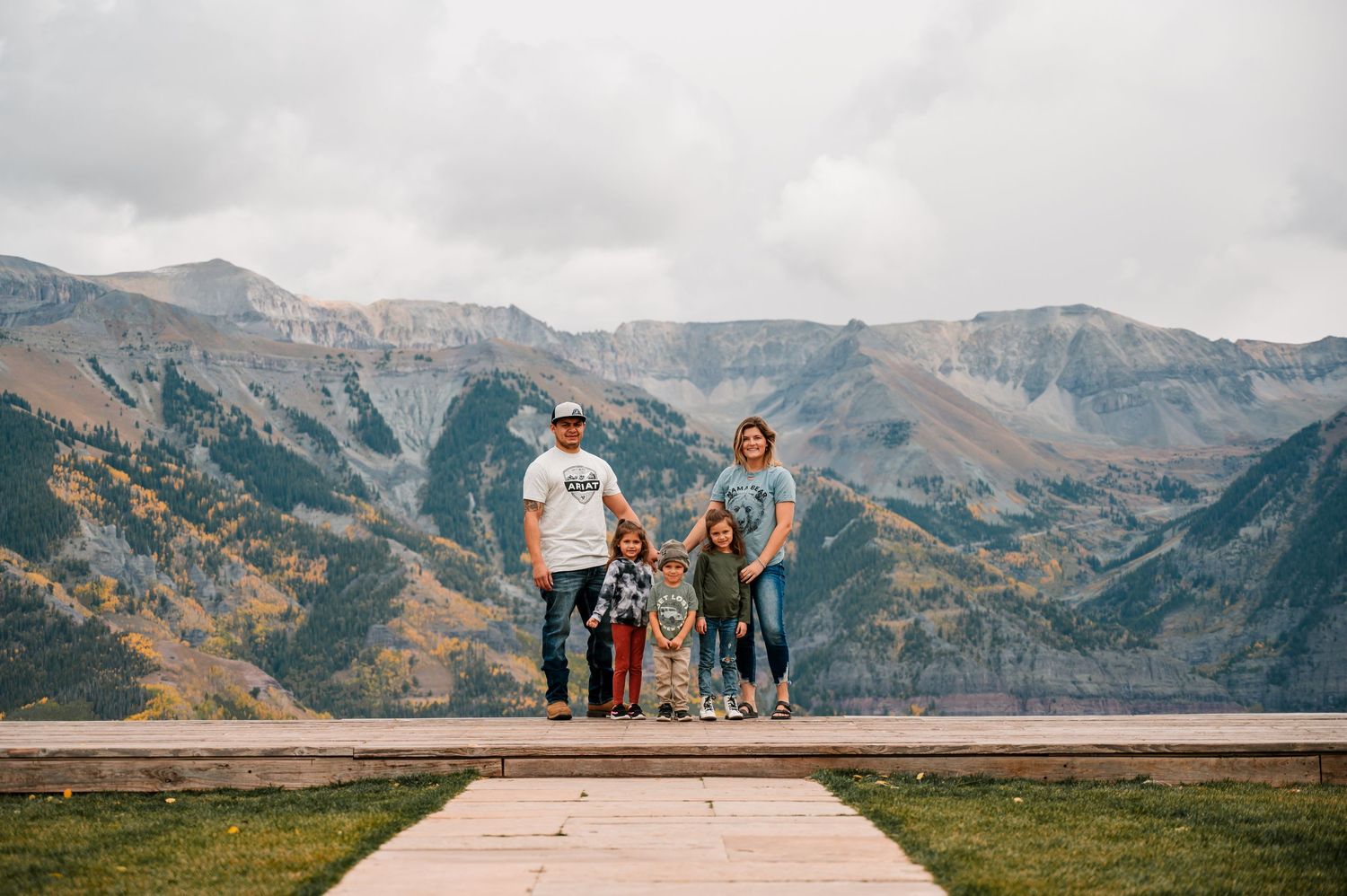 A family stands together against a backdrop of majestic mountain peaks and autumn colors.