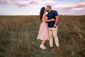 Romantic sunset engagement photo in tall grass field during golden hour.