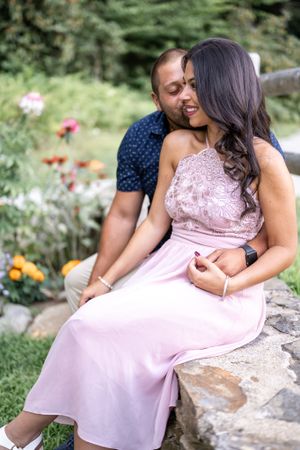A tender moment captured between a couple on stone steps with blooming flowers in the background.