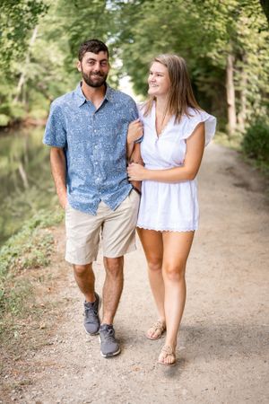 A couple takes a romantic stroll together on a nature path wearing coordinated summer outfits.