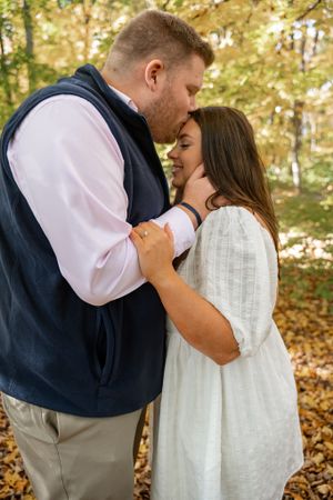 A tender embrace captured during an autumn engagement photoshoot in a wooded setting.