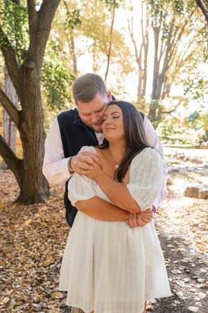 A couple shares a romantic moment in dappled sunlight during their fall engagement session.