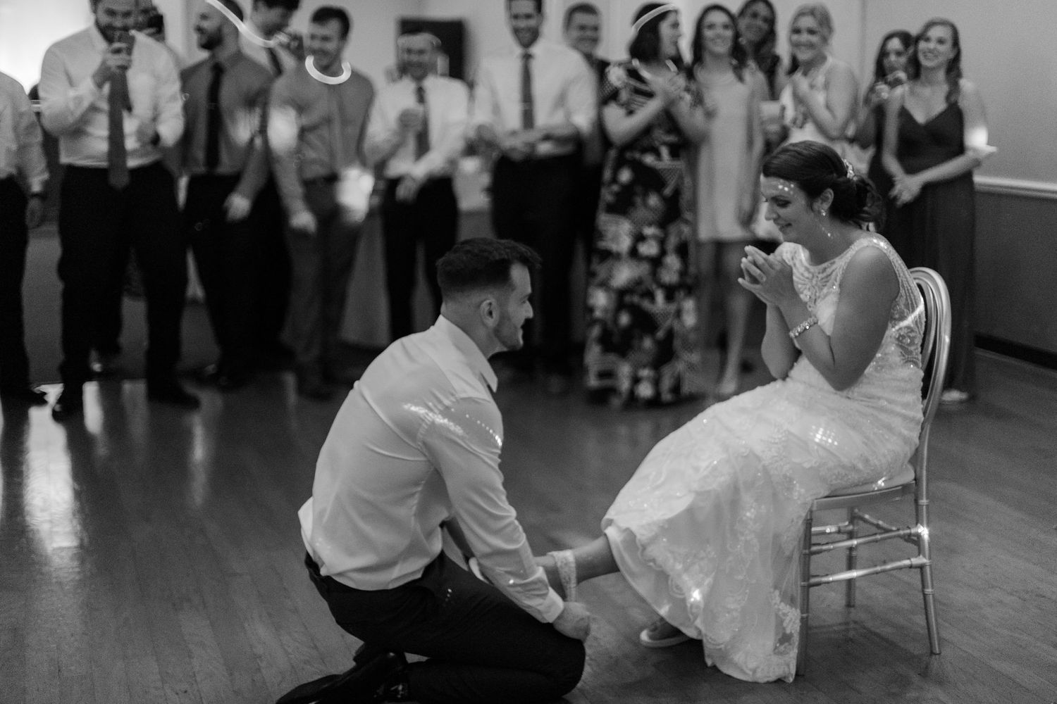 Black and white photo of wedding guests dancing and celebrating at a reception.