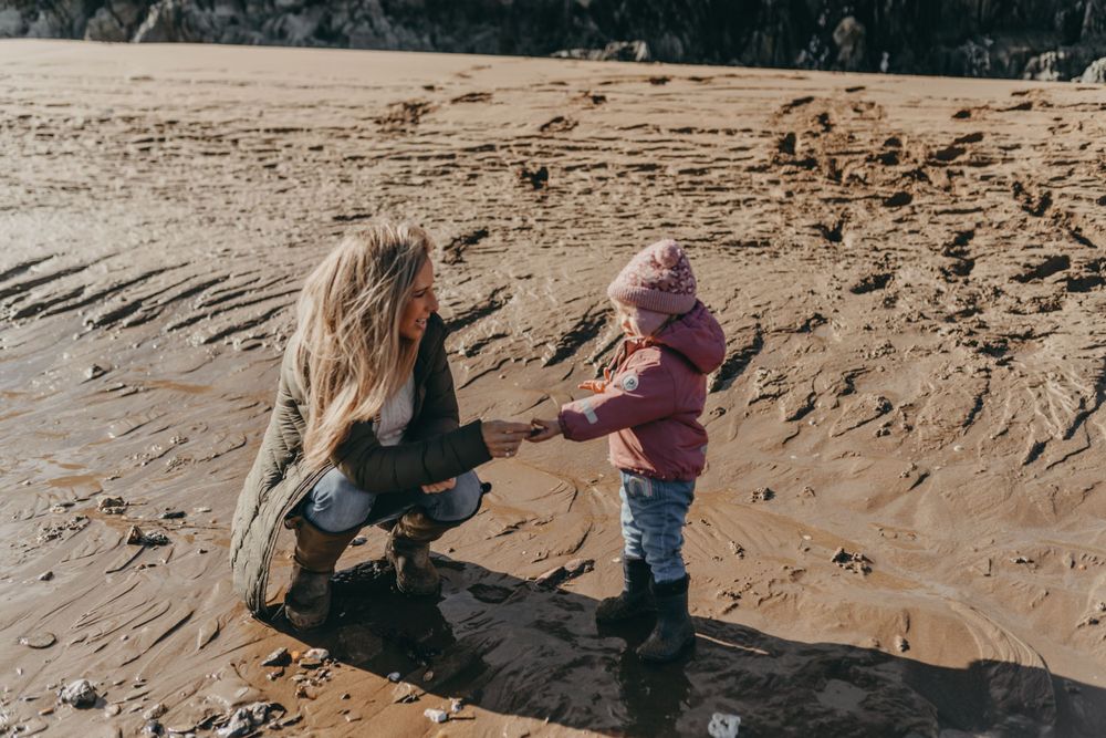A tender moment shared on a sandy beach during a cloudy day.