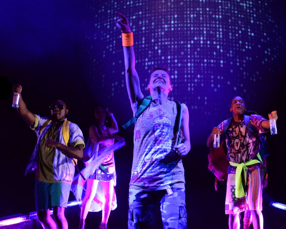 Performers raise their arms in celebration under sparkling digital backdrop effects.