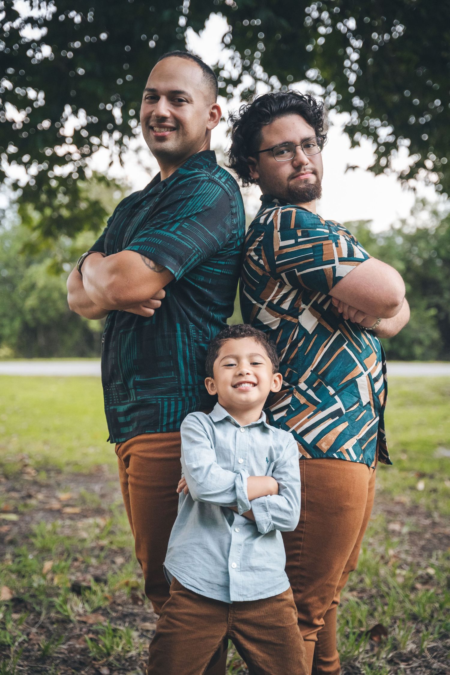 Three people posing together outdoors wearing coordinated blue and brown outfits.