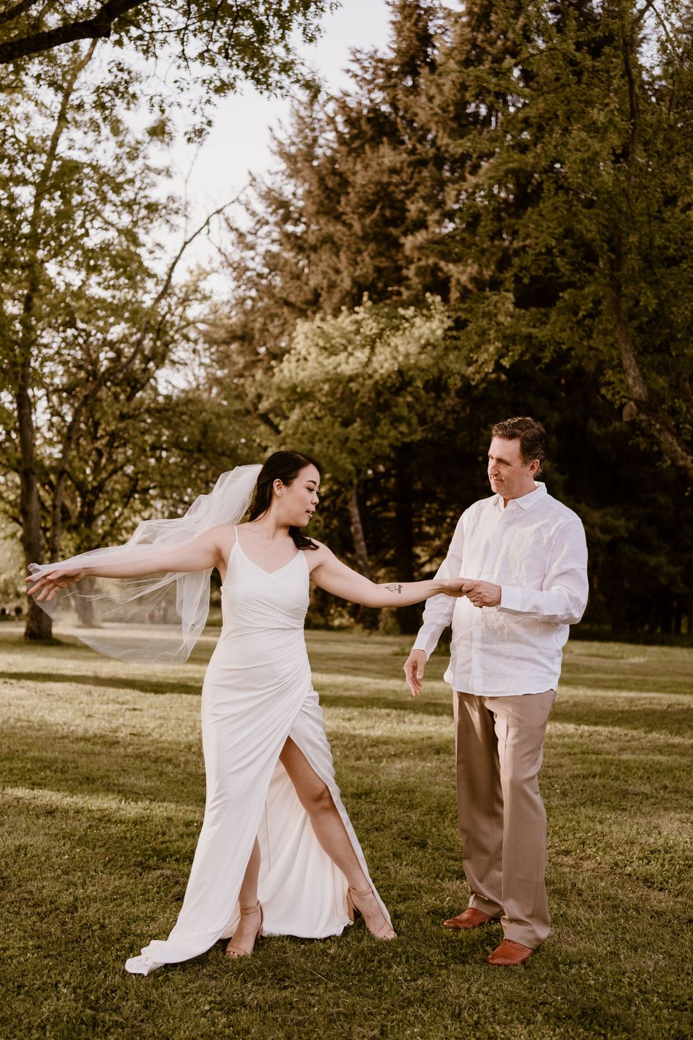 Playful dance moves on a grassy hillside in white outfits.