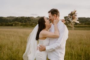 A romantic couple embraces in a sunlit field during golden hour.