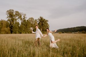 Two figures walking through a golden field during sunset.