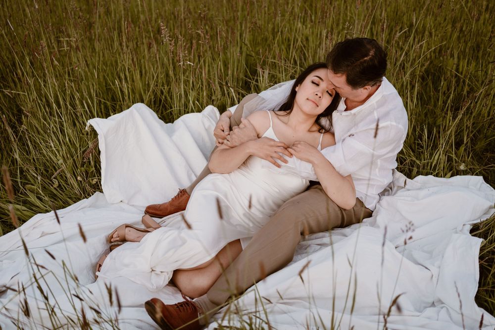 A couple relaxes together in tall grass during an intimate photo session.