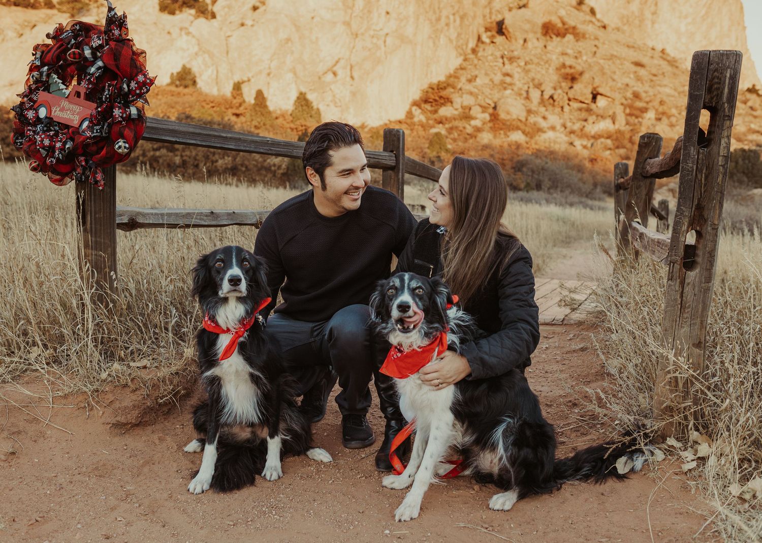 a couple looking at each other fondly with their two dogs at sunrise
