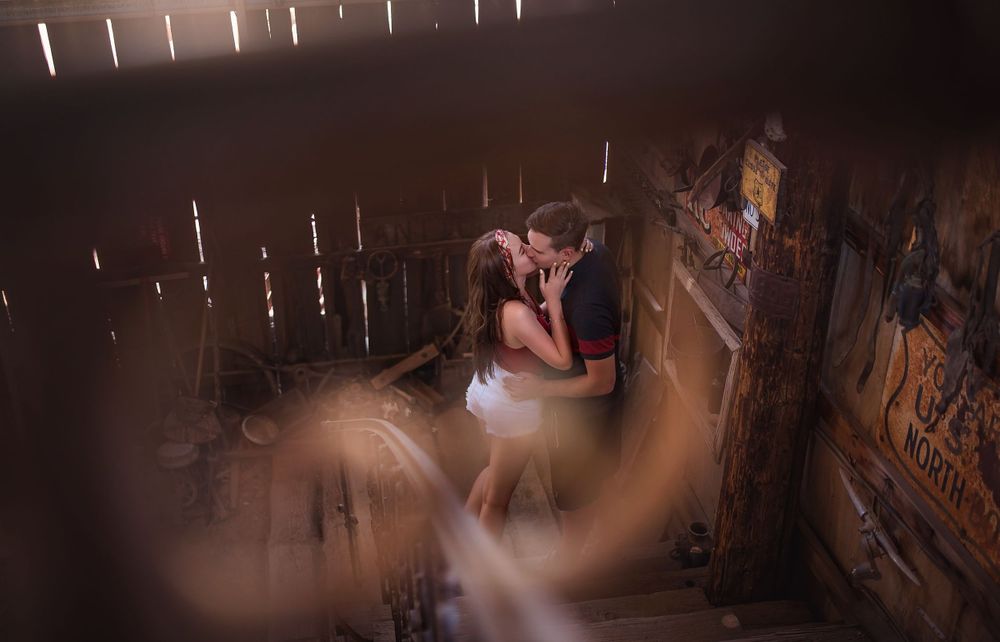 A dreamy romantic moment captured through wooden slats in dim atmospheric lighting.