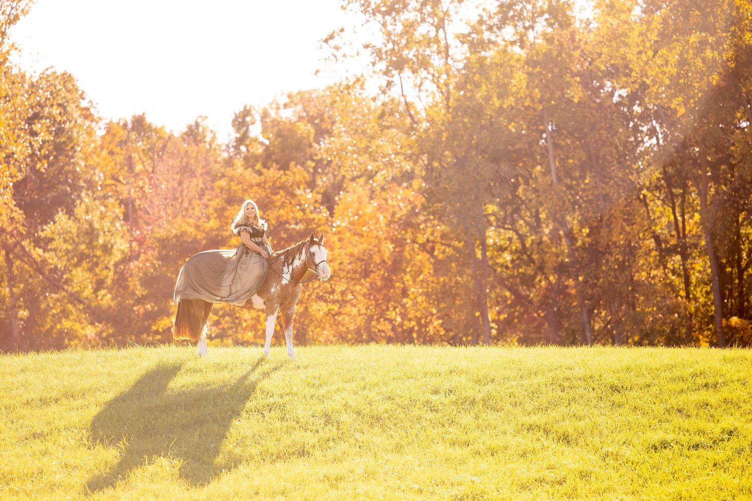 Girl in flowy dress on her paint mare in a field in the fall
