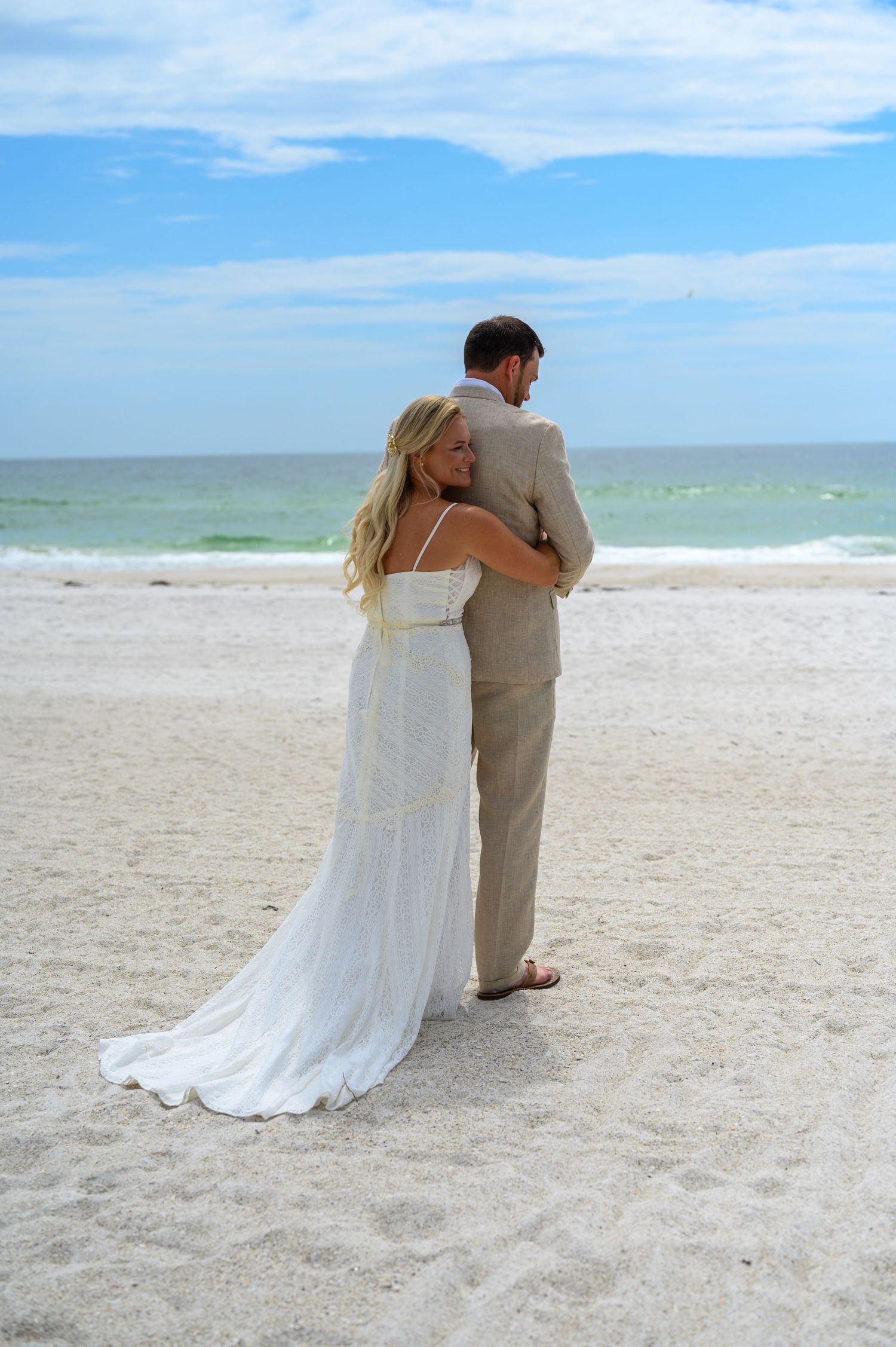 Bride hugging groom from behind.