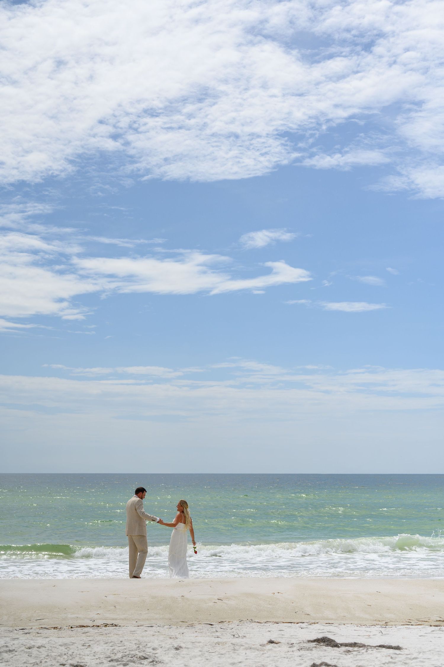 Bride and Groom walking on beach.