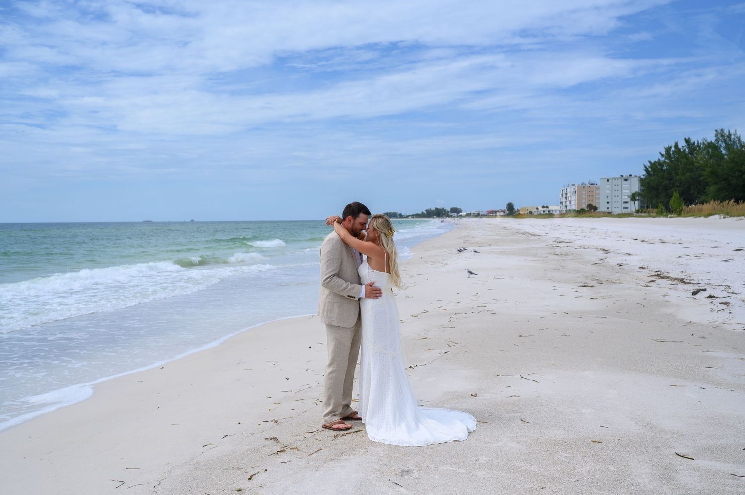 Bride and Groom hug on beach.