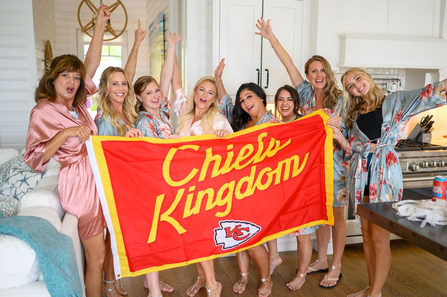 Bridal party pose behind NFL Chiefs flag