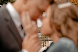 An artistic close-up shot of a couple with architectural details blurred in background.
