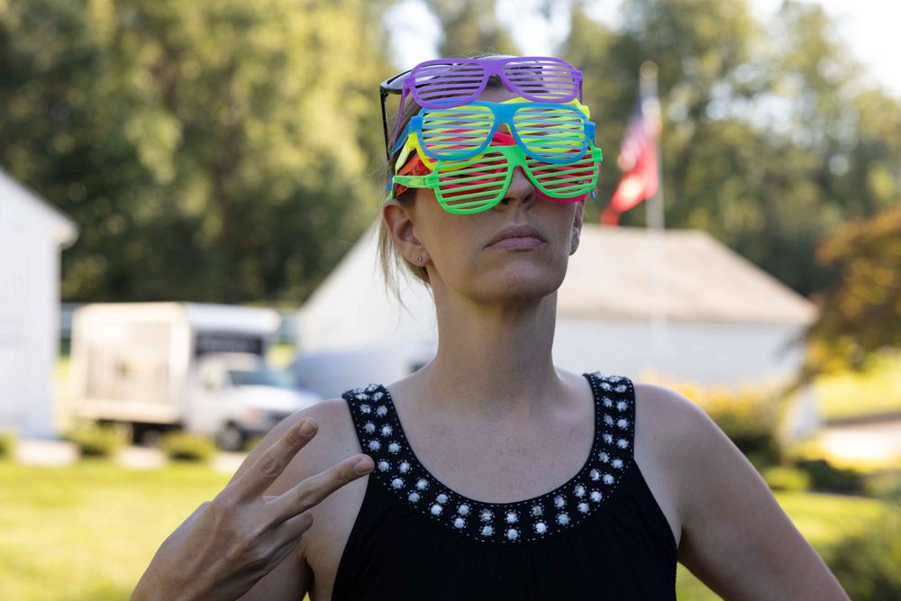 Person wearing colorful stacked sunglasses outdoors in summer.