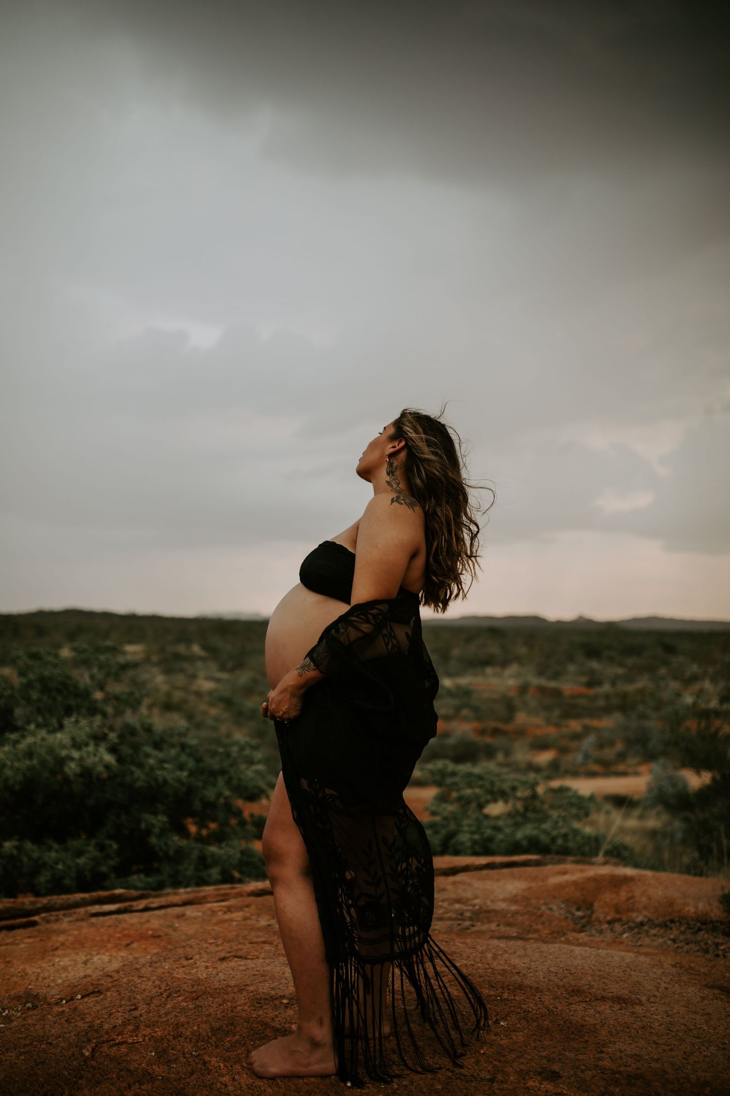 Beautiful mama to be poses on a hill at Granite Mines, Mount Isa