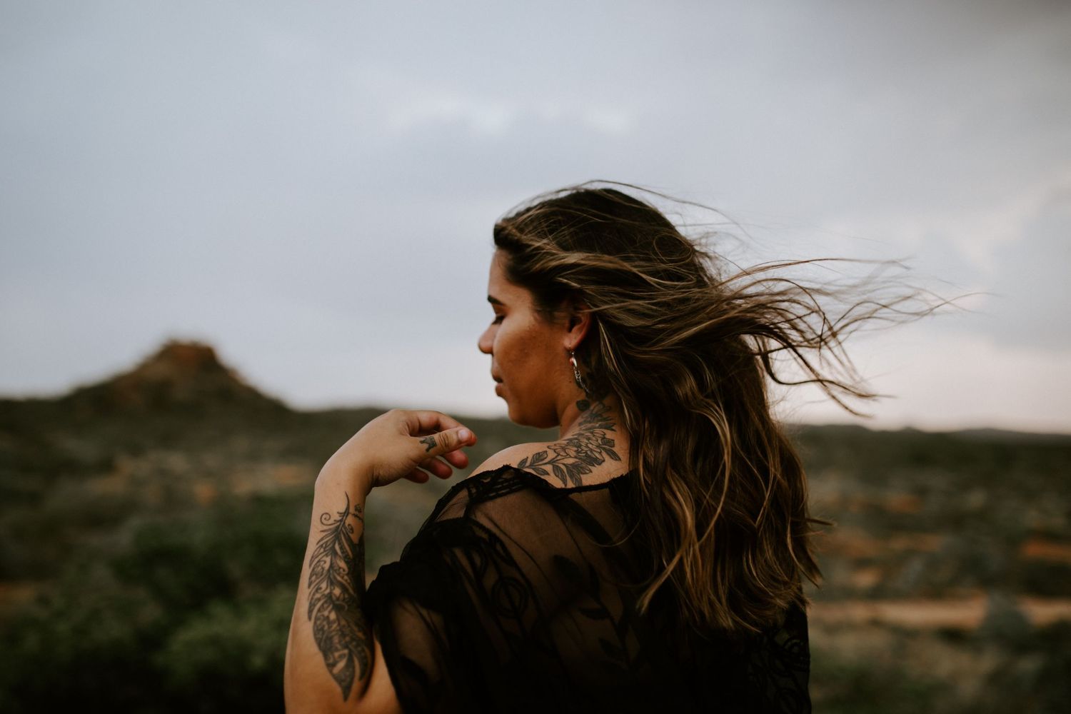 Beautiful mama to be poses on a hill at Granite Mines, Mount Isa with wind blowing in her hair