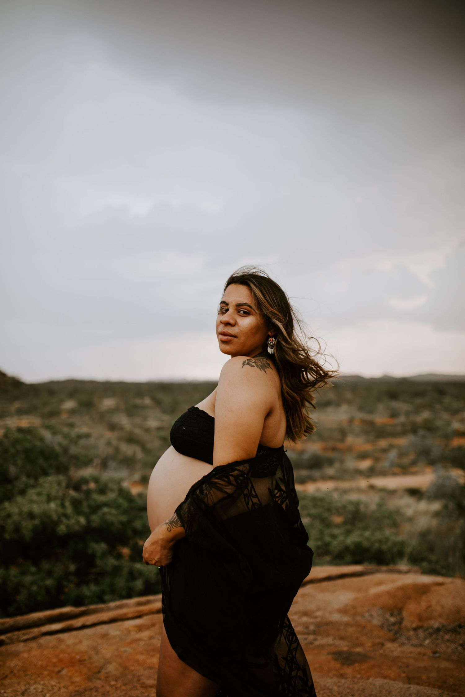 Beautiful mama to be poses on a hill at Granite Mines, Mount Isa up close portrait