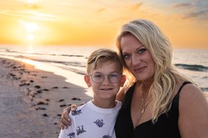 Mother and son share a tender moment on the beach during golden hour.