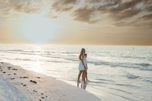 Silhouette of person walking alone on beach at sunset with waves rolling in.