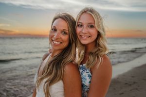 Two smiling companions pose together on the beach at sunset.