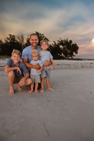 A family portrait taken at sunset on a sandy beach.