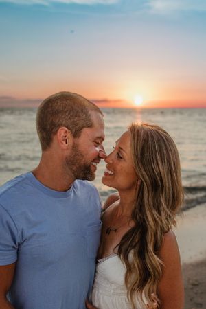 A couple shares an intimate moment on the beach during sunset.