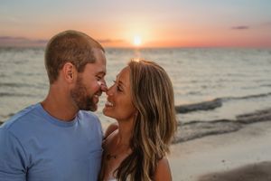 A romantic couple shares an intimate moment at sunset on the beach.