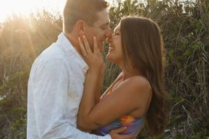 Intimate romantic moment captured between couple during golden hour with sunlight peeking through.
