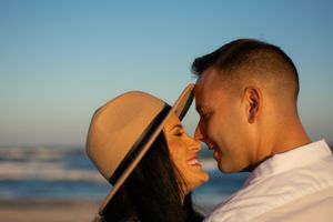 A couple shares an intimate moment on the beach during golden hour.