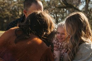 Candid family moment with laughter and embraces captured in natural outdoor setting.