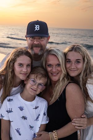 Family group photo at sunset on the beach with Detroit baseball cap and ocean backdrop.