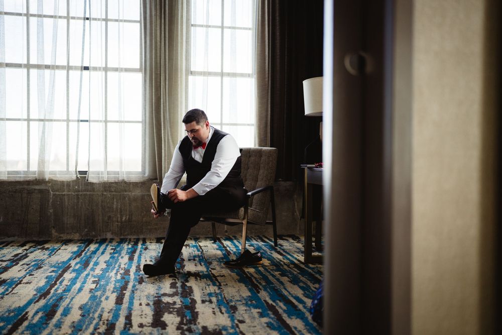 Person in formal attire sitting alone in contemplation by a window.