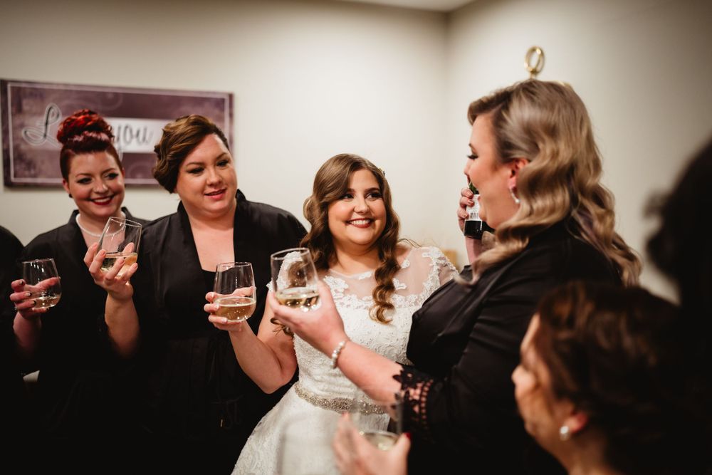 Wedding party members sharing drinks and laughter during celebration.