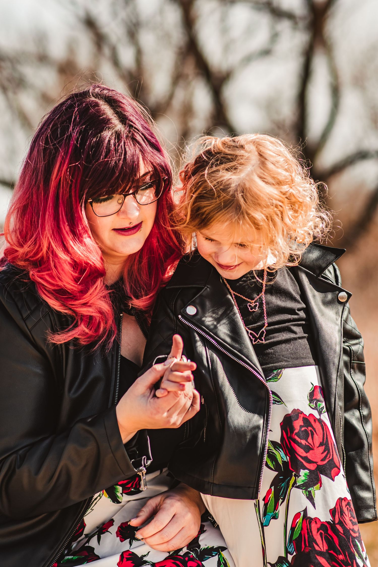 Two people in matching floral outfits and leather jackets share an intimate moment outdoors.