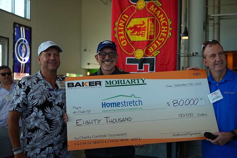 Large ceremonial check presentation with organizational banner display in background.