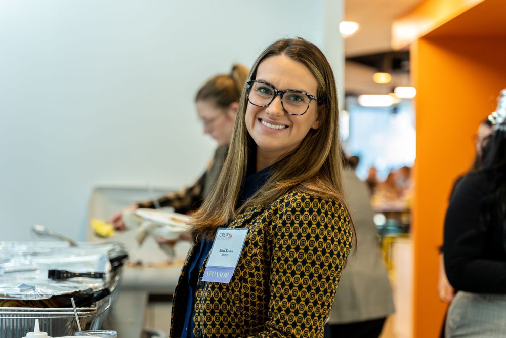 Event staff member greeting guests at registration table with warm smile.