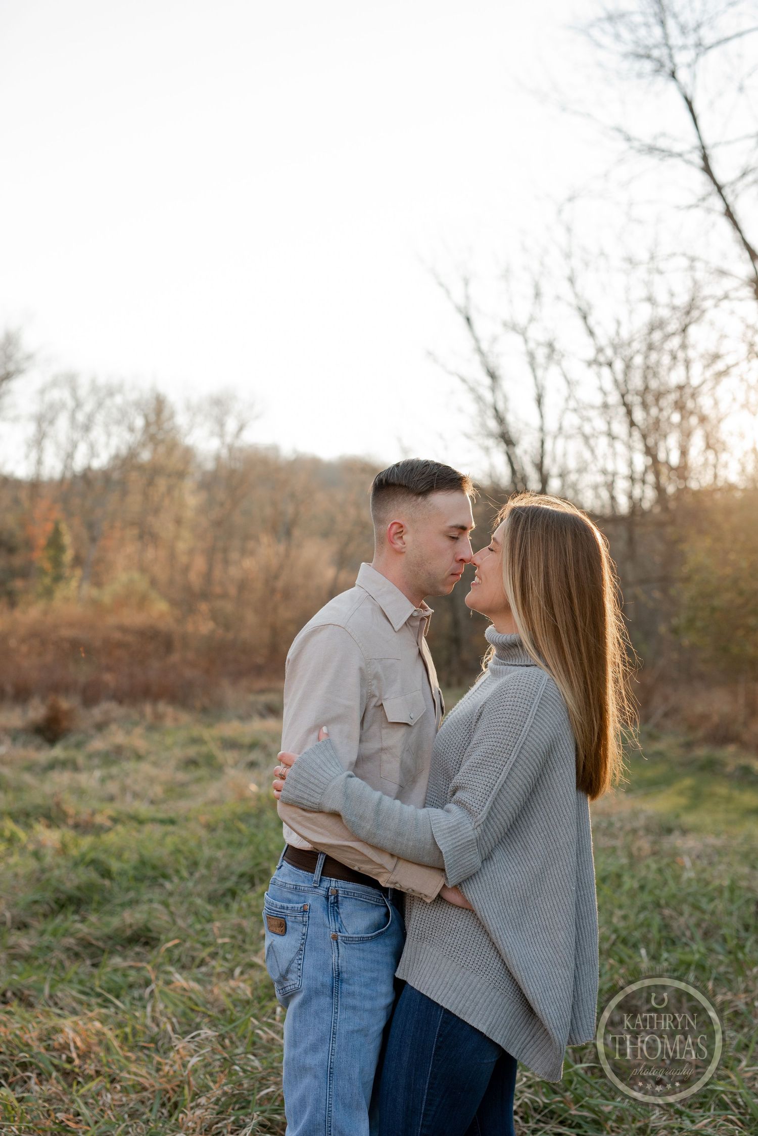A romantic couple shares an intimate moment in an autumn field with golden sunlight filtering through trees.