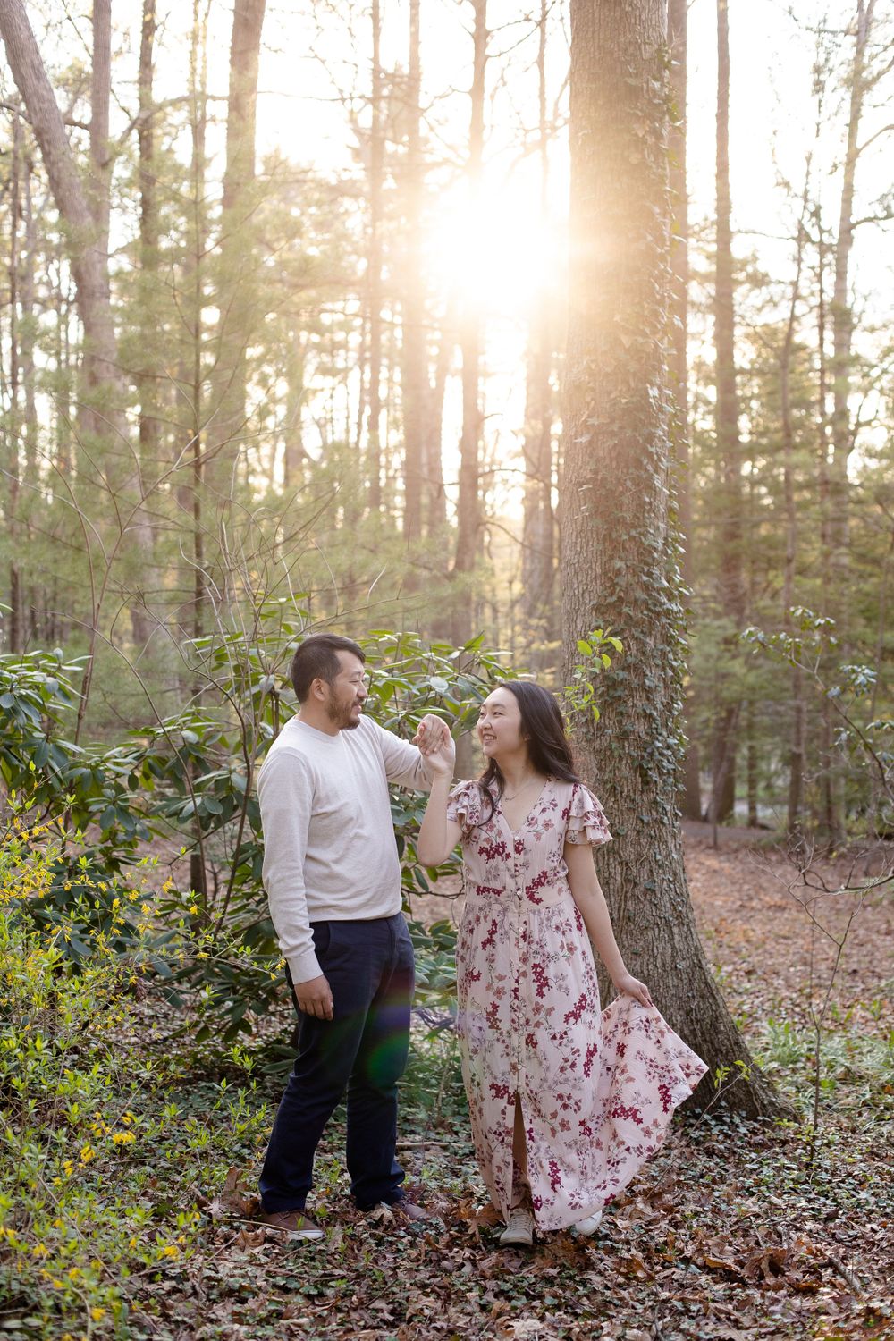 A romantic forest photoshoot with a couple in coordinated outfits against sunlit trees.