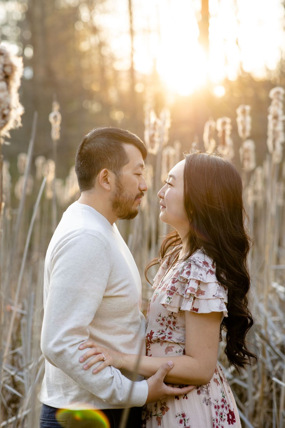 A romantic moment captured between a couple surrounded by sunlit cattails at golden hour.
